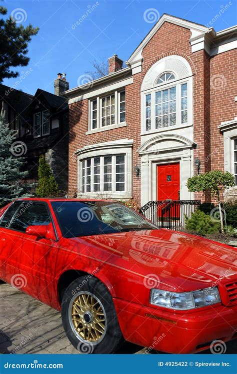 A Red Sports Car Parked In Front Of A White Building With A Black And