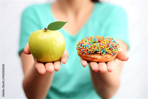 Hard To Choose Healthy Food Concept With Woman Hand Holding An Green Apple And A Calorie Bomb