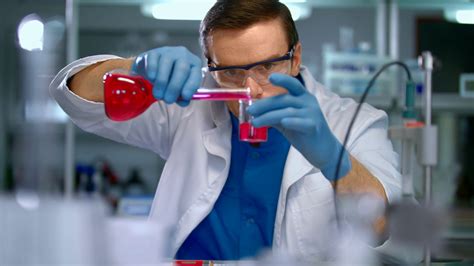 Scientist In Lab Doing Medical Research Laboratory Worker Pour Liquid From Flask To Measuring